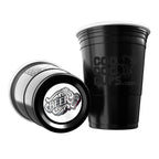 Two black CooCoo Cups® are shown. One displays the logo while the other lies on its side, revealing a bottom sticker featuring a cool “BEER” text and graphic.