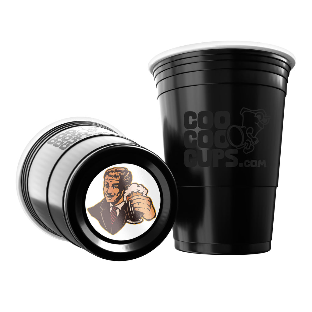 Two black CooCoo Cups® are shown. One displays the logo while the other lies on its side, revealing a bottom sticker with a charismatic guy holding a beer and raising a toast.