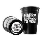 Two black CooCoo Cups® are shown. One displays the white text “Happy Birthday To You!” while the other lies on its side, revealing a customizable bottom sticker labeled “Your Design Here.”