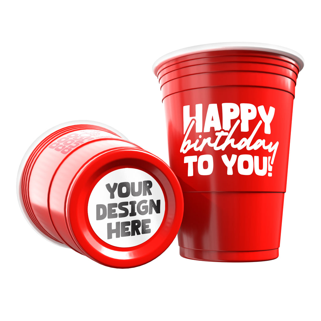 Red party cup with 'Happy Birthday To You!' text and another cup laying down showing its bottom sticker with 'Your Design Here' customizable area on a white background.