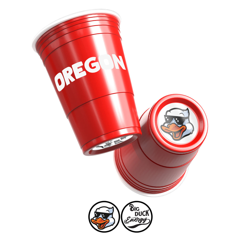 Two red CooCoo Cups® are shown displaying "Oregon" text and bottom stickers featuring “Big Duck Energy” and a cool duck with sunglasses graphic.