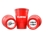 Three red CooCoo Cups® are shown. One displays "Florida" text, while the other two lie on their sides, revealing bottom stickers featuring gator imagery and “Chomp Chomp” designs.
